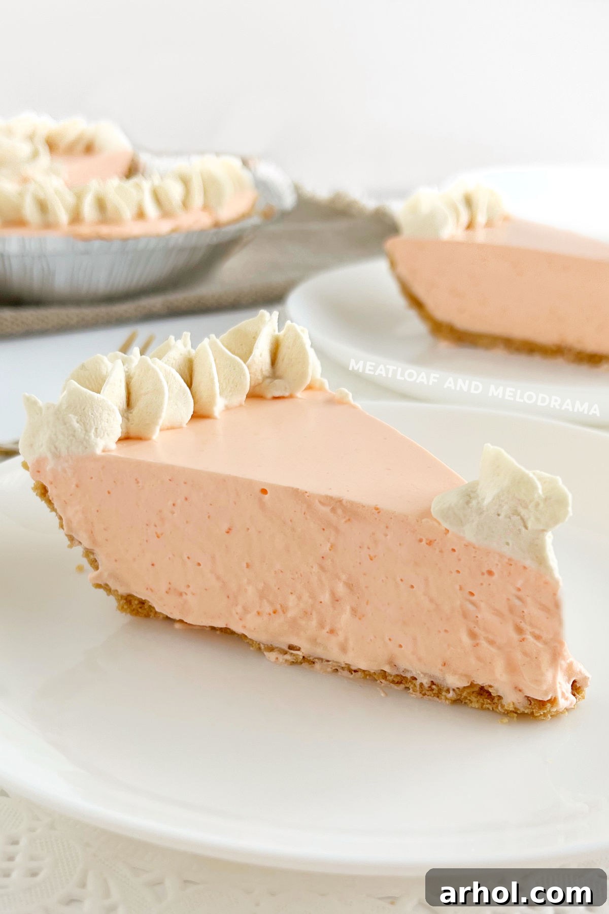 Slices of fluffy orange creamsicle pie, garnished with whipped cream and a hint of orange zest, served on elegant plates.
