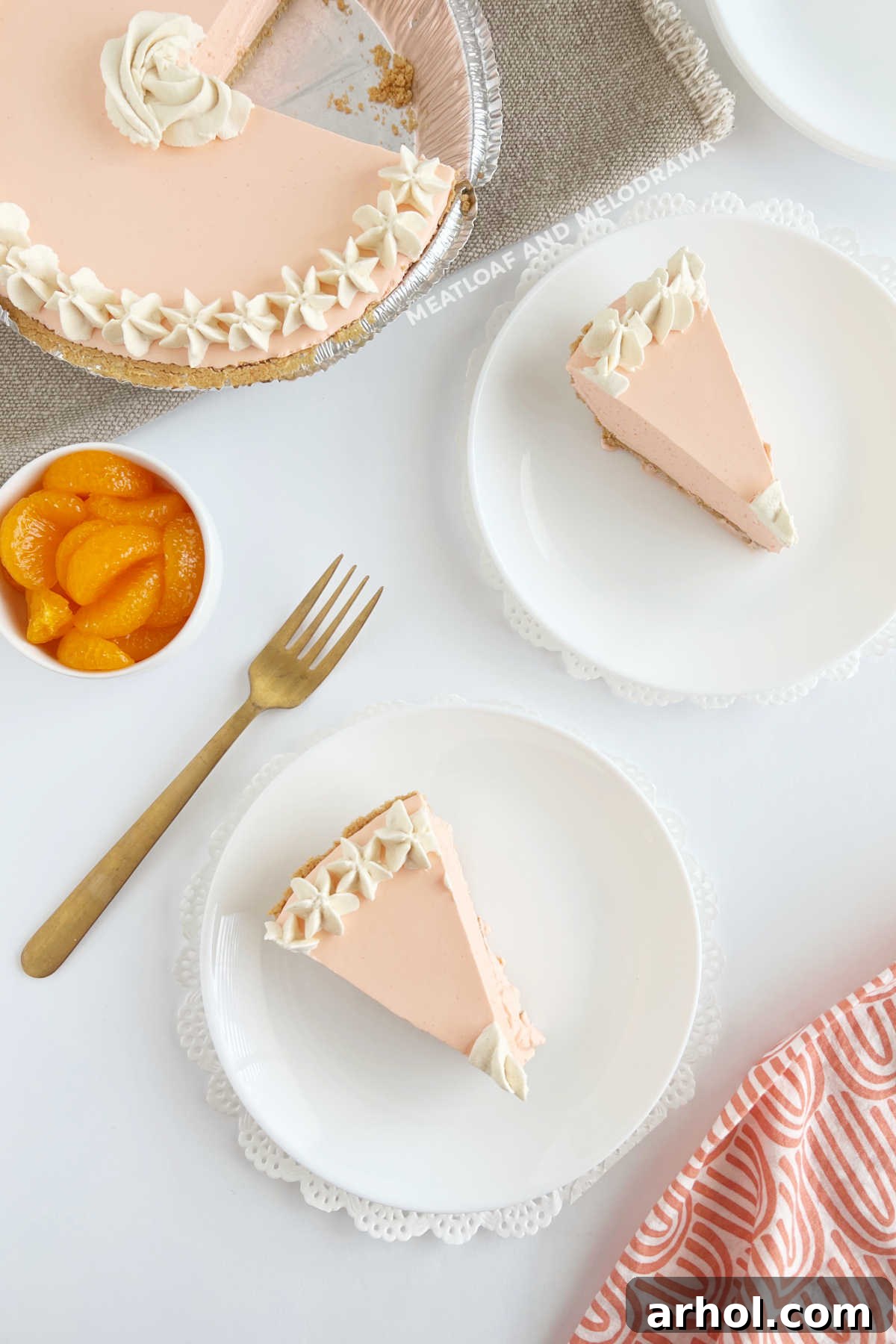 A vibrant orange creamsicle pie, generously topped with fluffy whipped cream and fresh mandarin orange slices, presented on a rustic wooden table, ready to be served.