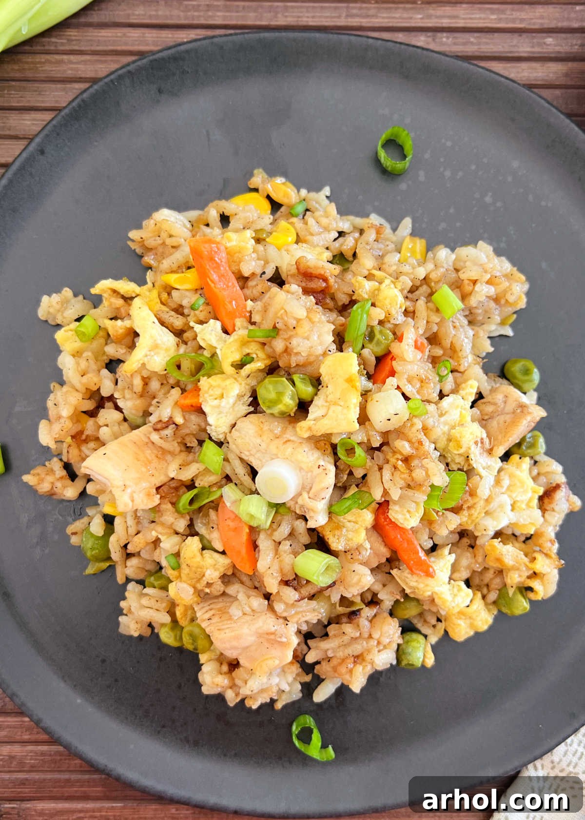 blackstone chicken fried rice with egg and vegetables and green onions on plate, garnished with fresh green onions and a drizzle of soy sauce