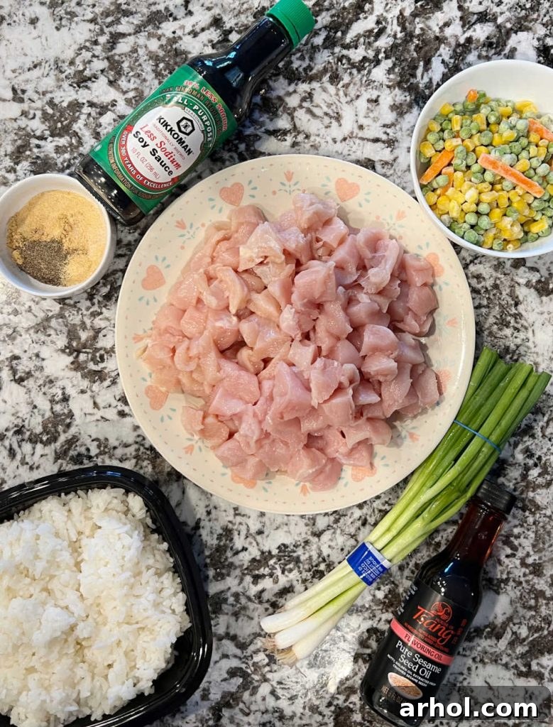 chicken breast cubed, jasmine rice, soy sauce, sesame sauce, frozen veggies, onions and spices laid out as ingredients