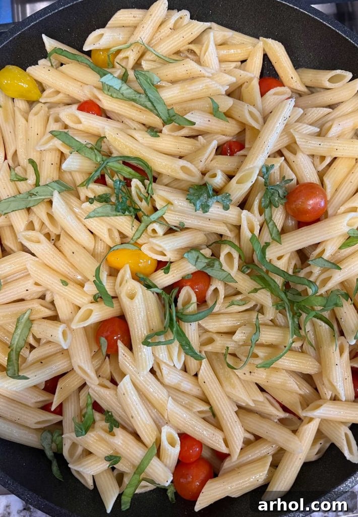 stir penne pasta with fresh basil and cherry tomatoes in skillet