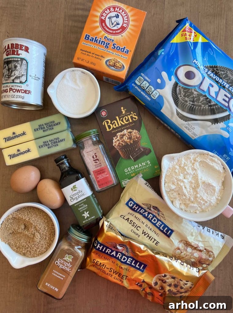 Essential ingredients for Oreo Chocolate Chip Cookies: Oreos, flour, sugar, brown sugar, baking soda, baking powder, eggs, butter, vanilla extract, salt, and various chocolates arranged neatly.