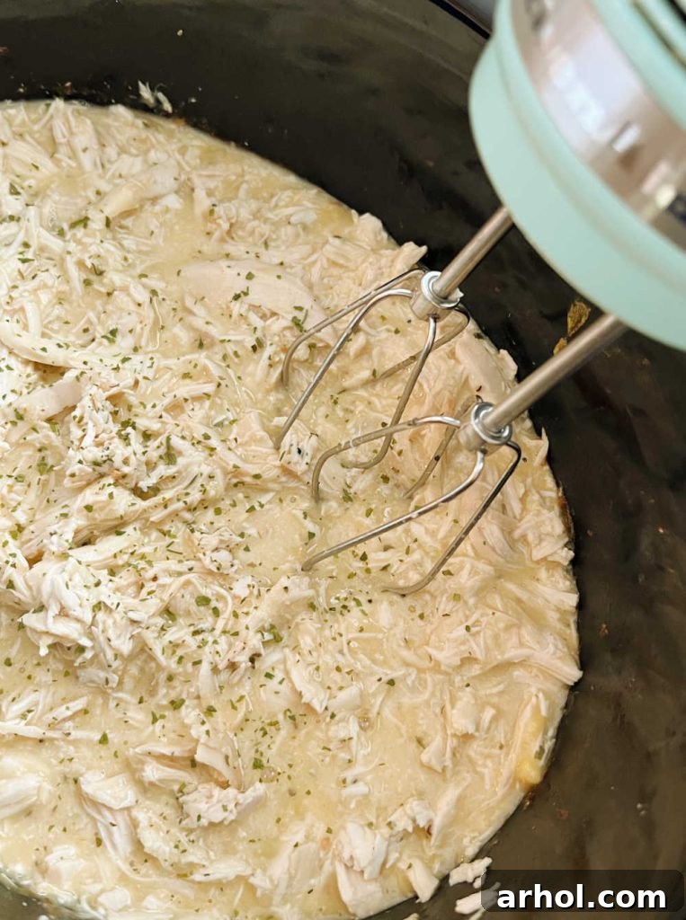 shred chicken with hand mixer in slow cooker