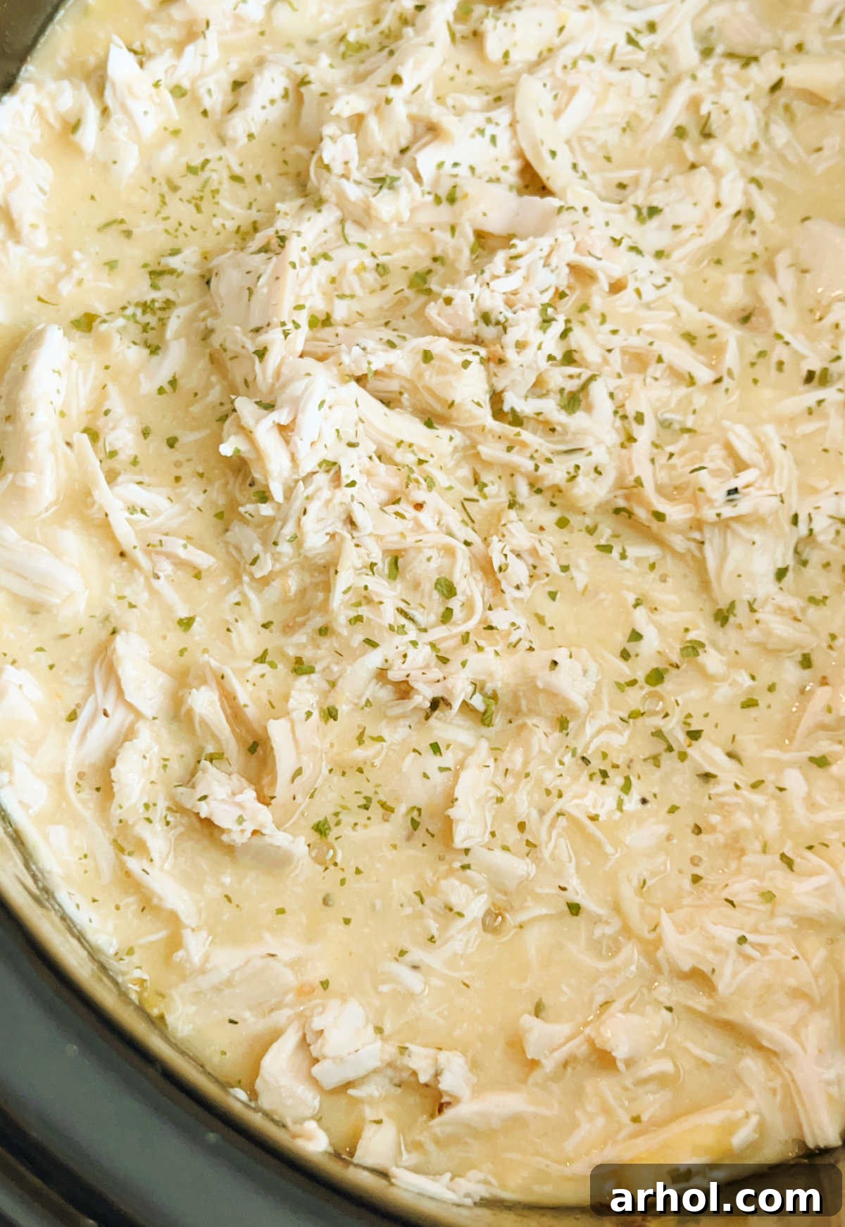 shredded chicken and gravy with parsley in crockpot
