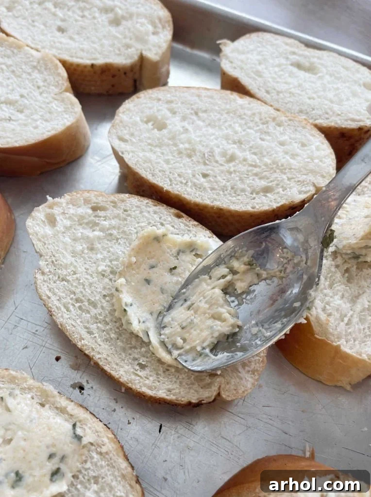 Spreading garlic butter on bread slices with spoon