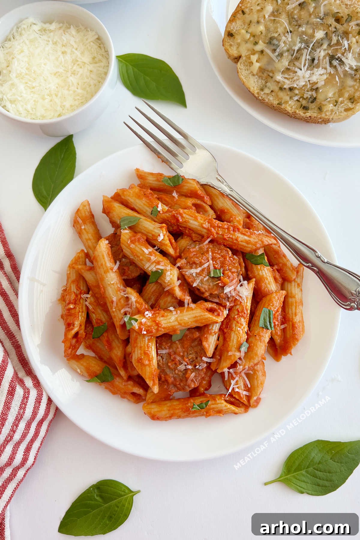 A plate of Penne alla Vodka with Italian sausage and a side of garlic bread.