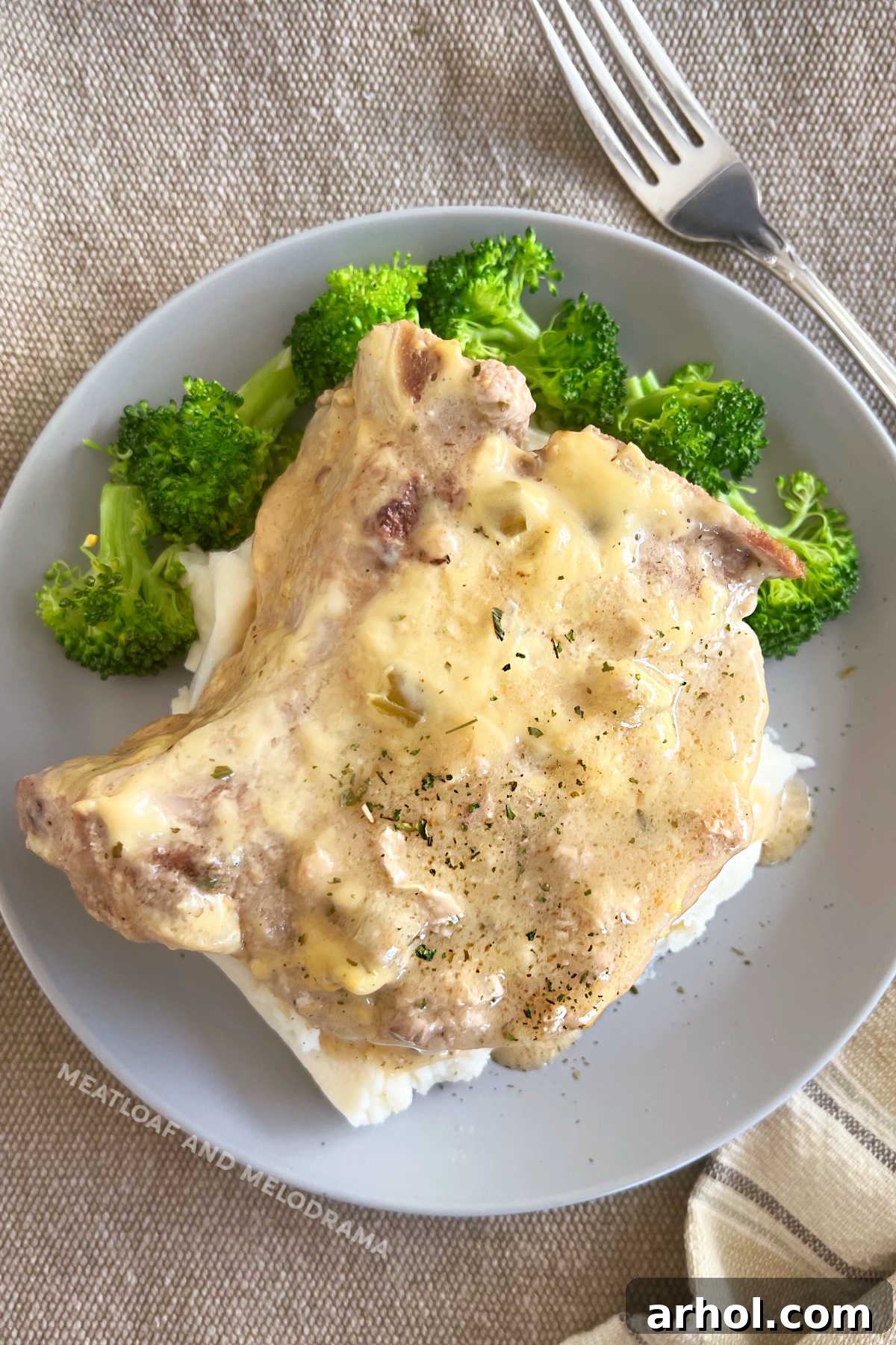bone-in pork chop with creamy gravy over mashed potatoes and broccoli
