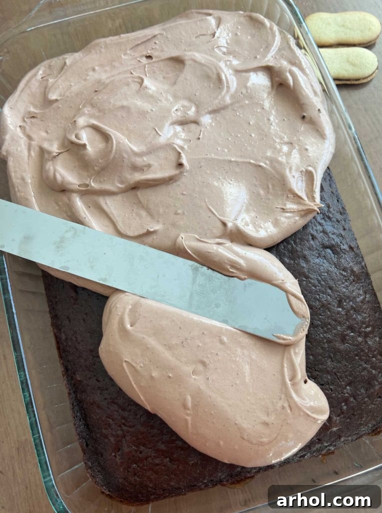 An image depicting the process of spreading the creamy chocolate pudding frosting evenly over the cooled chocolate cake in a baking dish, creating a smooth and delicious top layer.