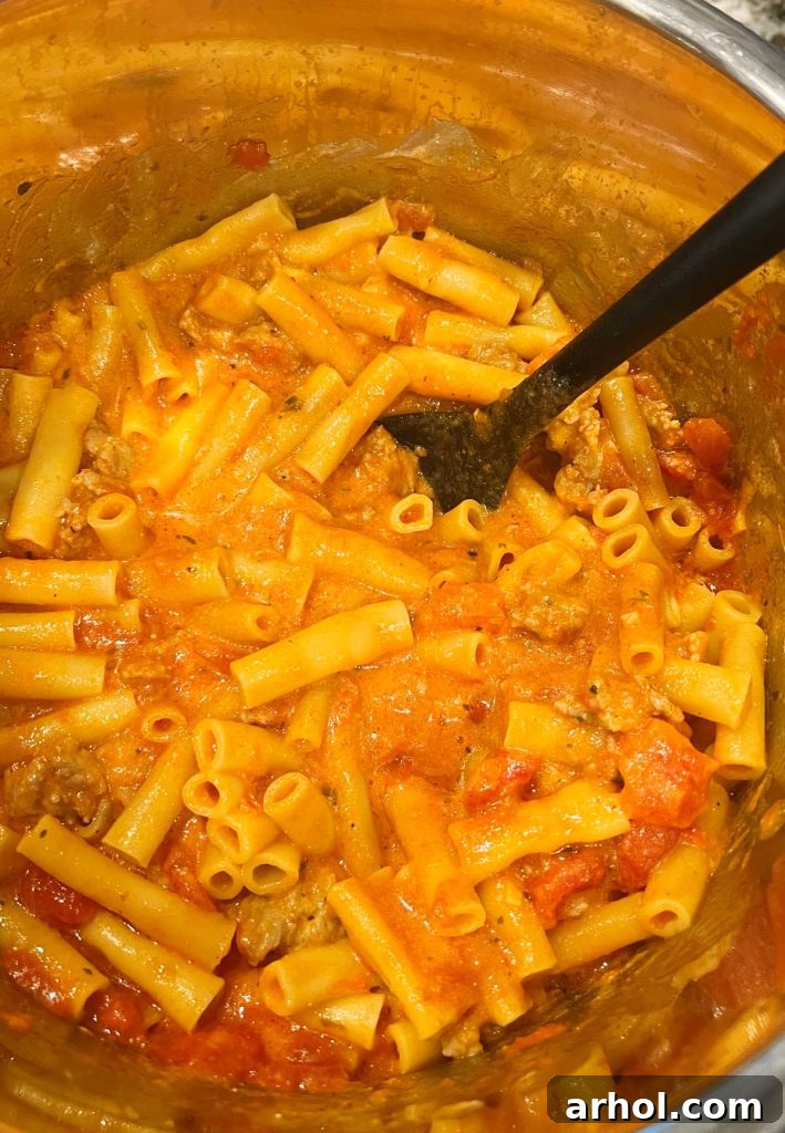Stirring cooked ziti with sausage and ricotta in Instant Pot