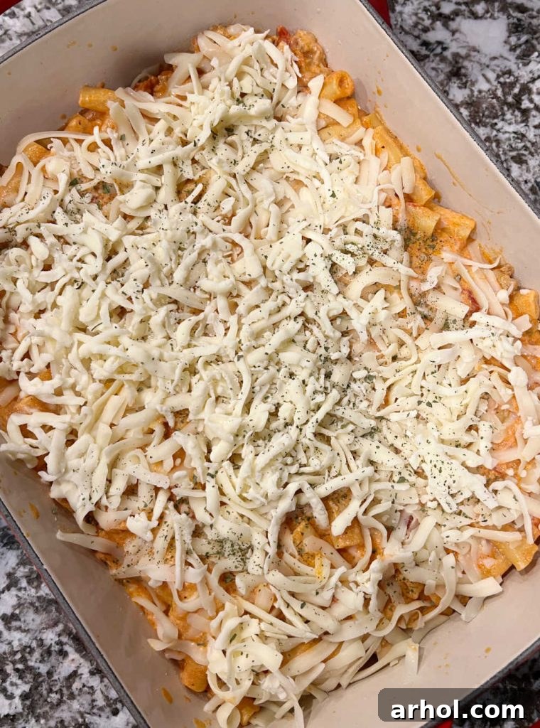 Layering ziti in a casserole dish with mozzarella cheese on top, ready for baking
