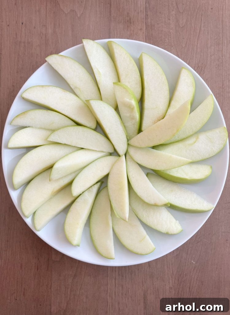 Caramel Apple Nacho Delight 4 Freshly cut, bright green apple slices meticulously arranged on a clean white serving platter, perfectly prepared and ready for the next delightful additions.