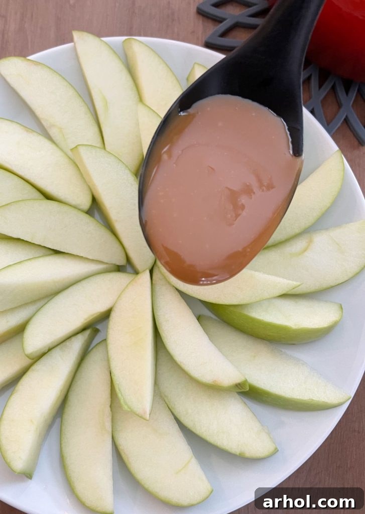 Caramel Apple Nacho Delight 5 Warm, golden caramel sauce being expertly drizzled in fine ribbons over a beautifully arranged platter of crisp green apple slices, creating an enticing pattern.