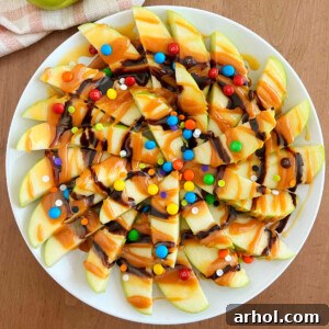 Caramel Apple Nacho Delight 7 A vibrant close-up of a platter showcasing slices of caramel apple nachos, generously topped with chocolate drizzles and an array of colorful candies, perfectly ready to be served.