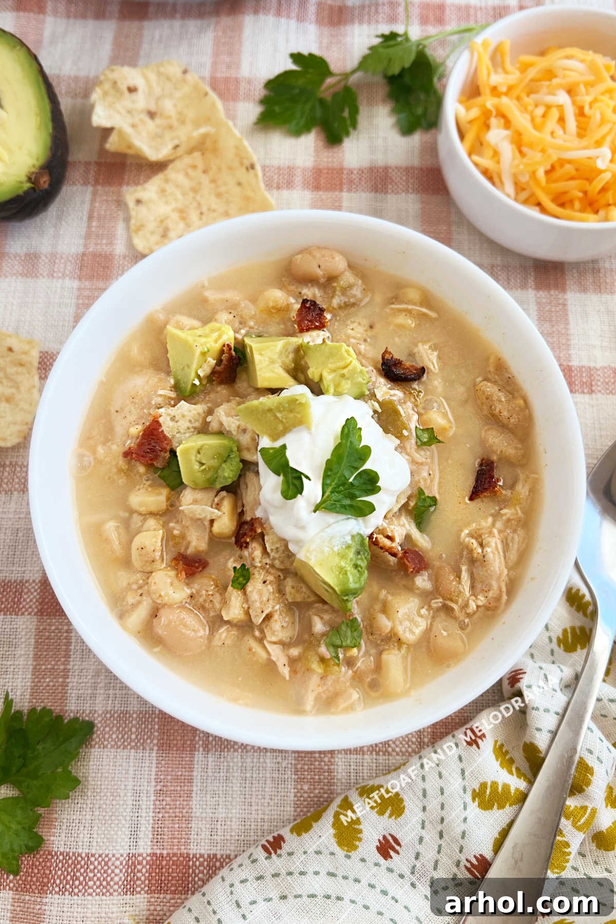 slow cooker white chicken chili with sour cream and avocado in bowl