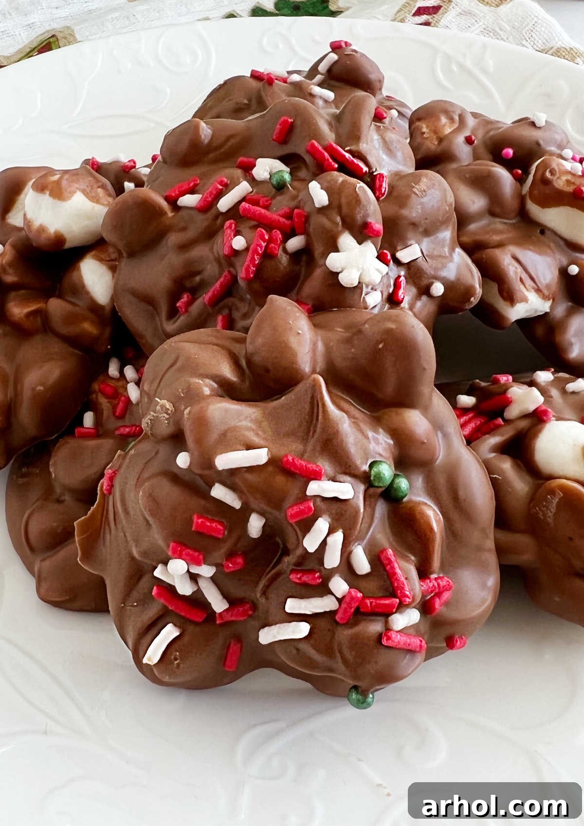 Delicious Crockpot Christmas Candy peanut clusters adorned with colorful sprinkles and mini marshmallows, arranged beautifully on a festive plate.