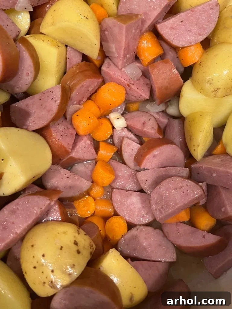 Kielbasa smoked sausage with potatoes and carrots beginning to simmer in a Dutch oven