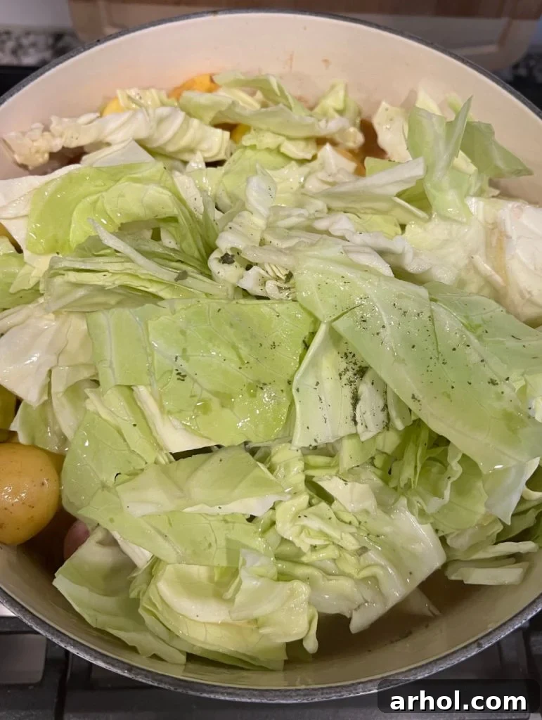 Chopped cabbage being added to the pot with potatoes and other vegetables