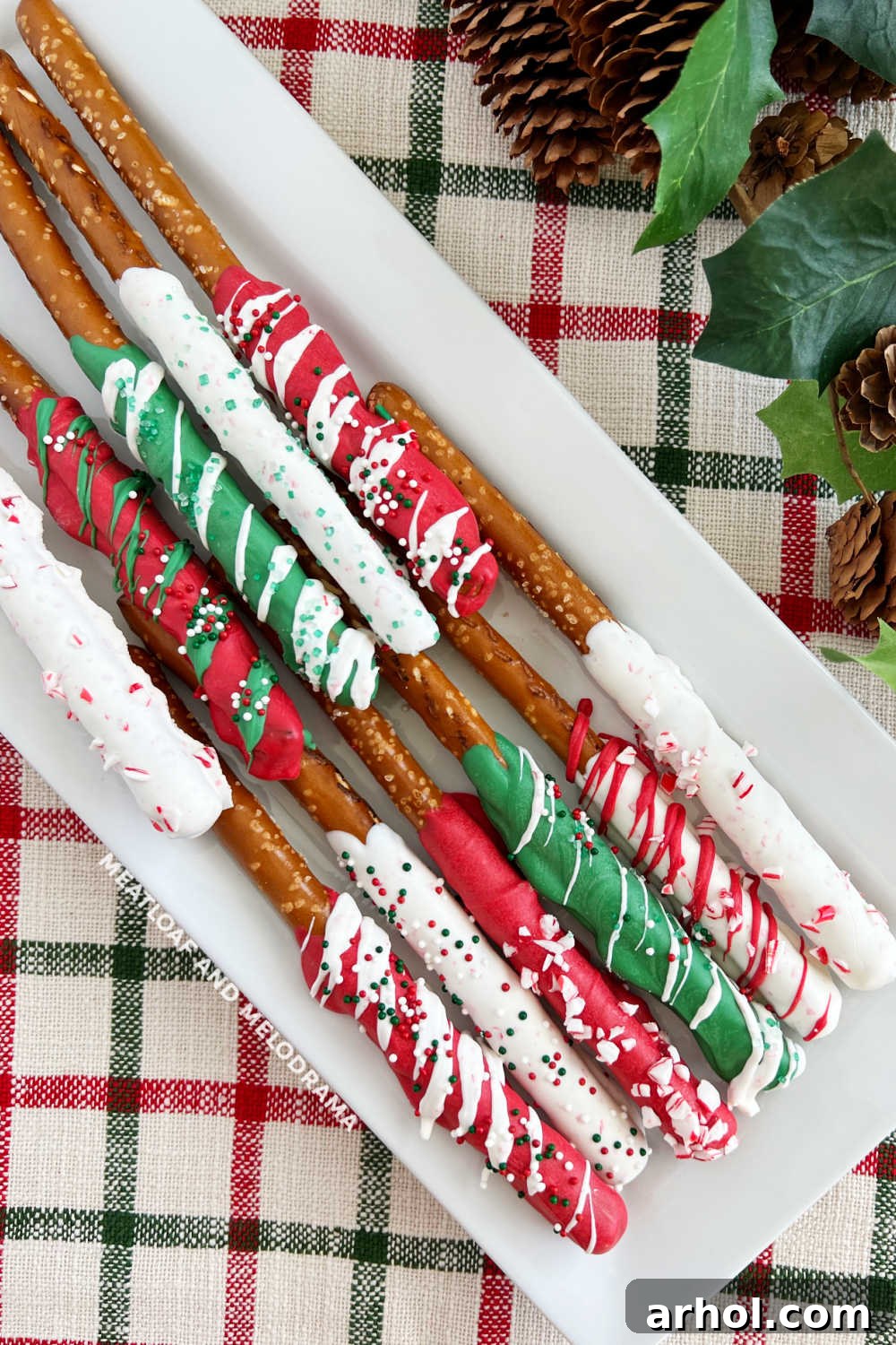 red, white and green chocolate covered Christmas pretzel rods on platter, beautifully decorated with festive sprinkles