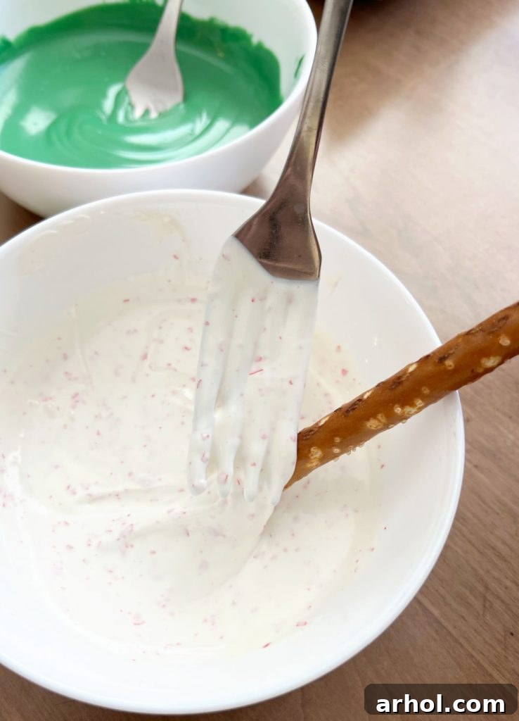 dipping a pretzel rod into melted white chocolate candy coating