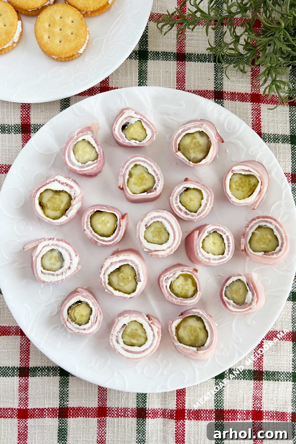 An elegant display of Ham Pickle Roll Ups on a white plate, set on a festive holiday table.