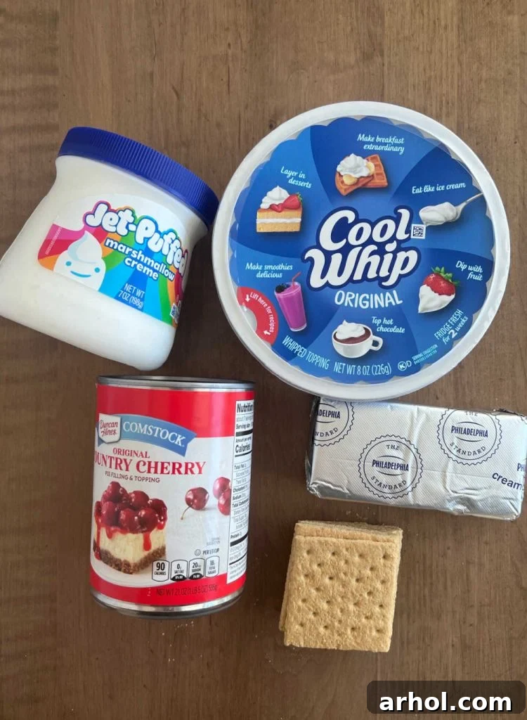 Luscious Cherry Cheesecake Dip 3 Key ingredients laid out for Cherry Cheesecake Dip: a can of cherry pie filling, marshmallow creme, Cool Whip tub, cream cheese block, and a stack of graham crackers.