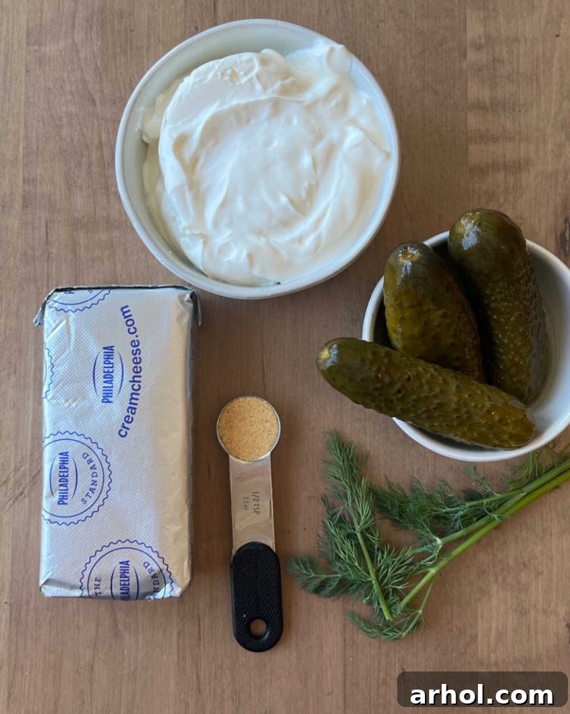 Sour cream, cream cheese, dill pickles, pickle juice, garlic powder, and fresh dill on a wooden board