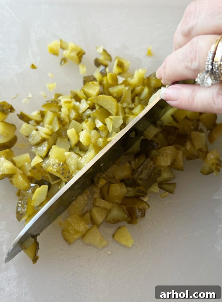 Finely chop dill pickles into small, uniform pieces on a cutting board