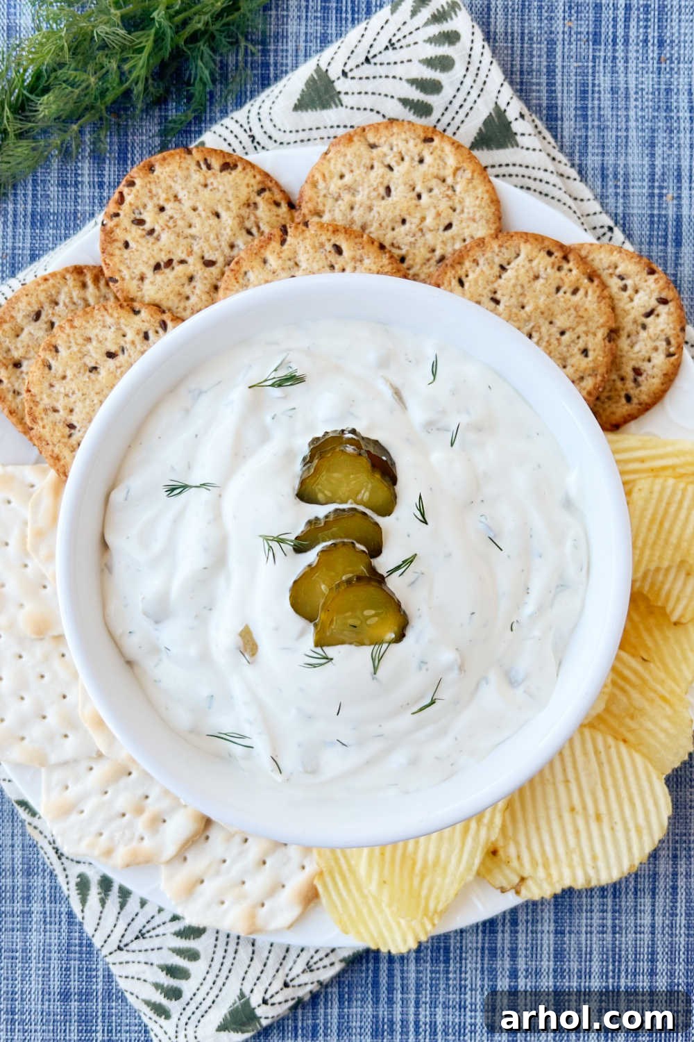 Dill pickle dip in a serving bowl with sliced pickles on top and fresh dill garnish