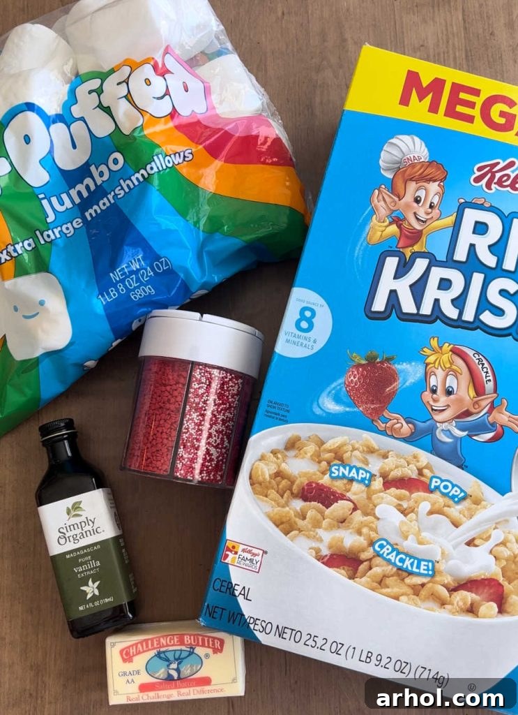 Ingredients for Rice Krispie Treats: jumbo marshmallows, box of Rice Krispies cereal, vanilla extract, butter, and festive sprinkles on a wooden surface