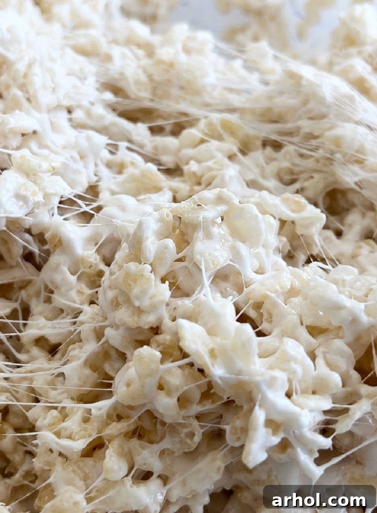 Mixing marshmallows and crispy rice cereal together until fully combined