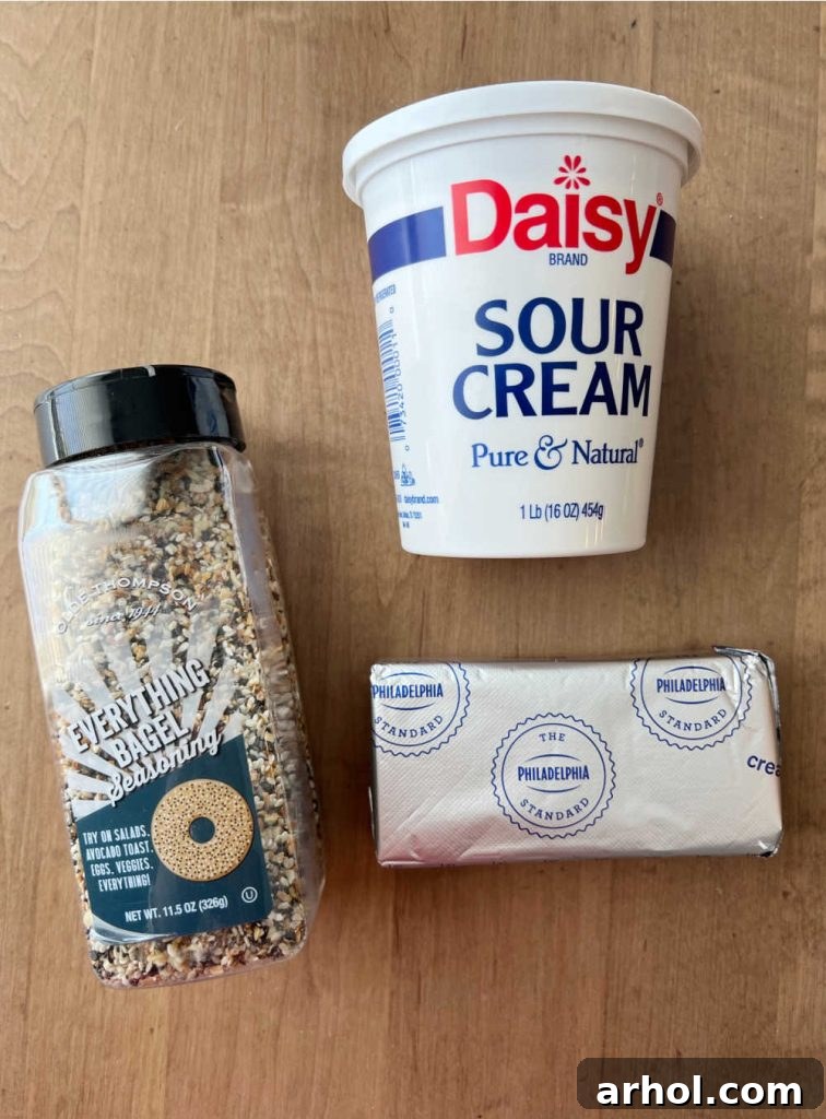 Individual ingredients: a block of cream cheese, a container of sour cream, and a jar of everything bagel seasoning blend.