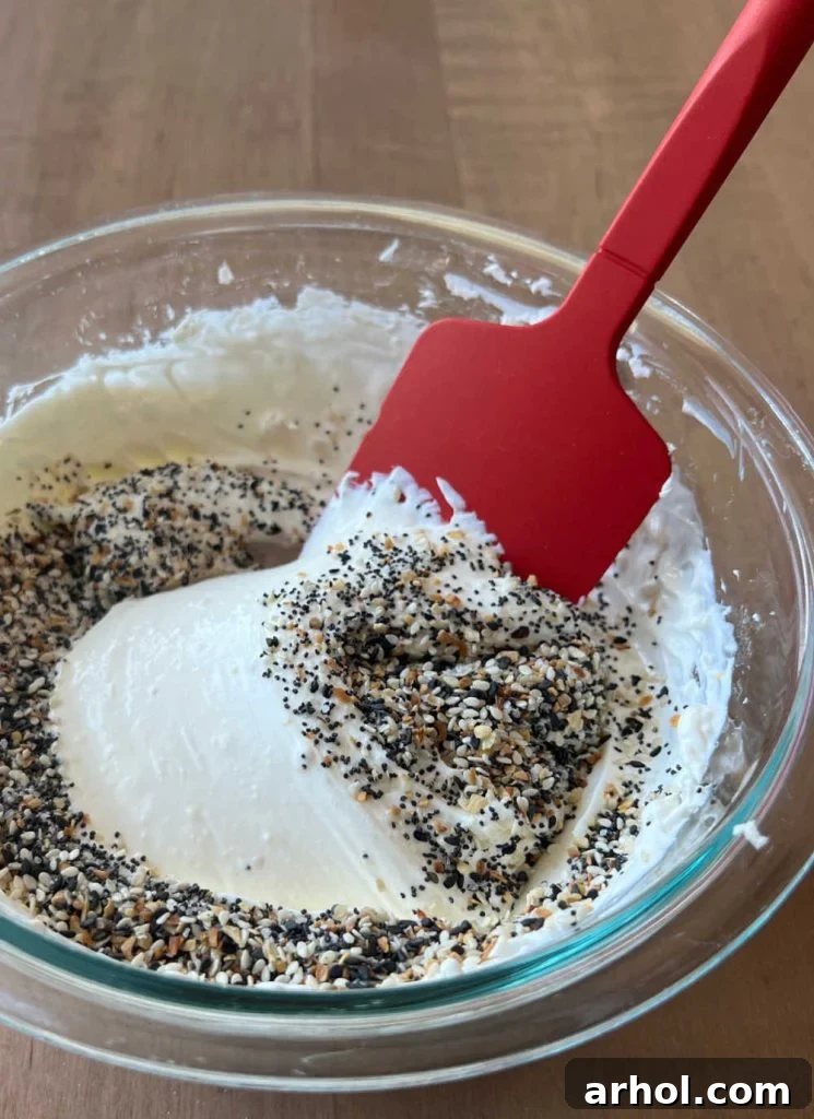 Mixing all the dip ingredients together thoroughly with a spatula in a bowl to ensure even distribution of seasoning.