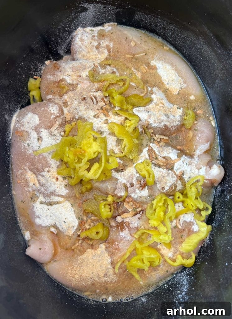 Effortless Mississippi Pot Roast Chicken 5 Raw chicken in slow cooker topped with onion soup mix, ranch dressing mix, and pepperoncini peppers.