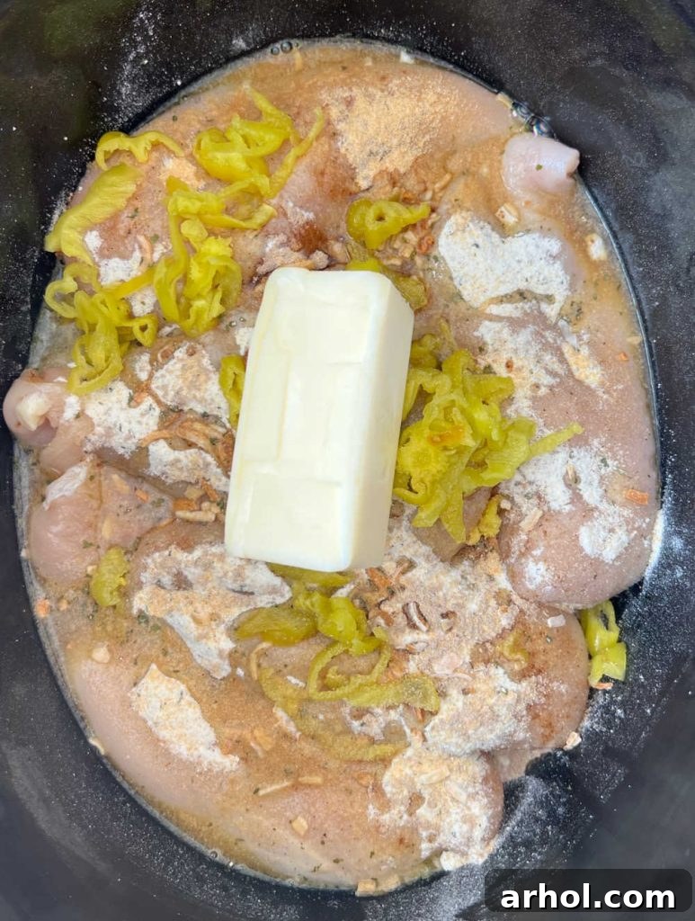 Effortless Mississippi Pot Roast Chicken 6 Mississippi chicken in slow cooker with butter on top.
