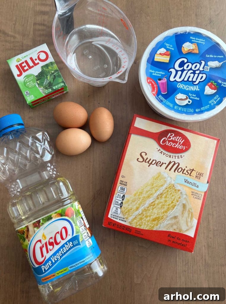 The simple ingredients laid out for Lime Jello Poke Cake: cake mix, eggs, lime Jell-O, water, vegetable oil, and a tub of Cool Whip.