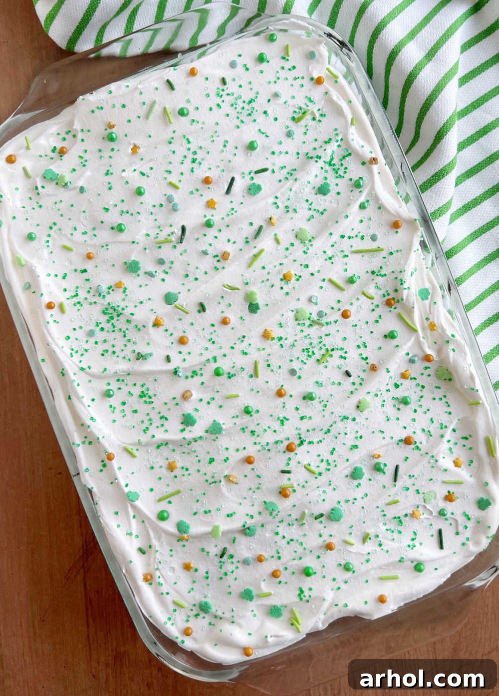 The finished Lime Jello Poke Cake in a baking dish, adorned with St. Patrick's Day sprinkles and ready for slicing.
