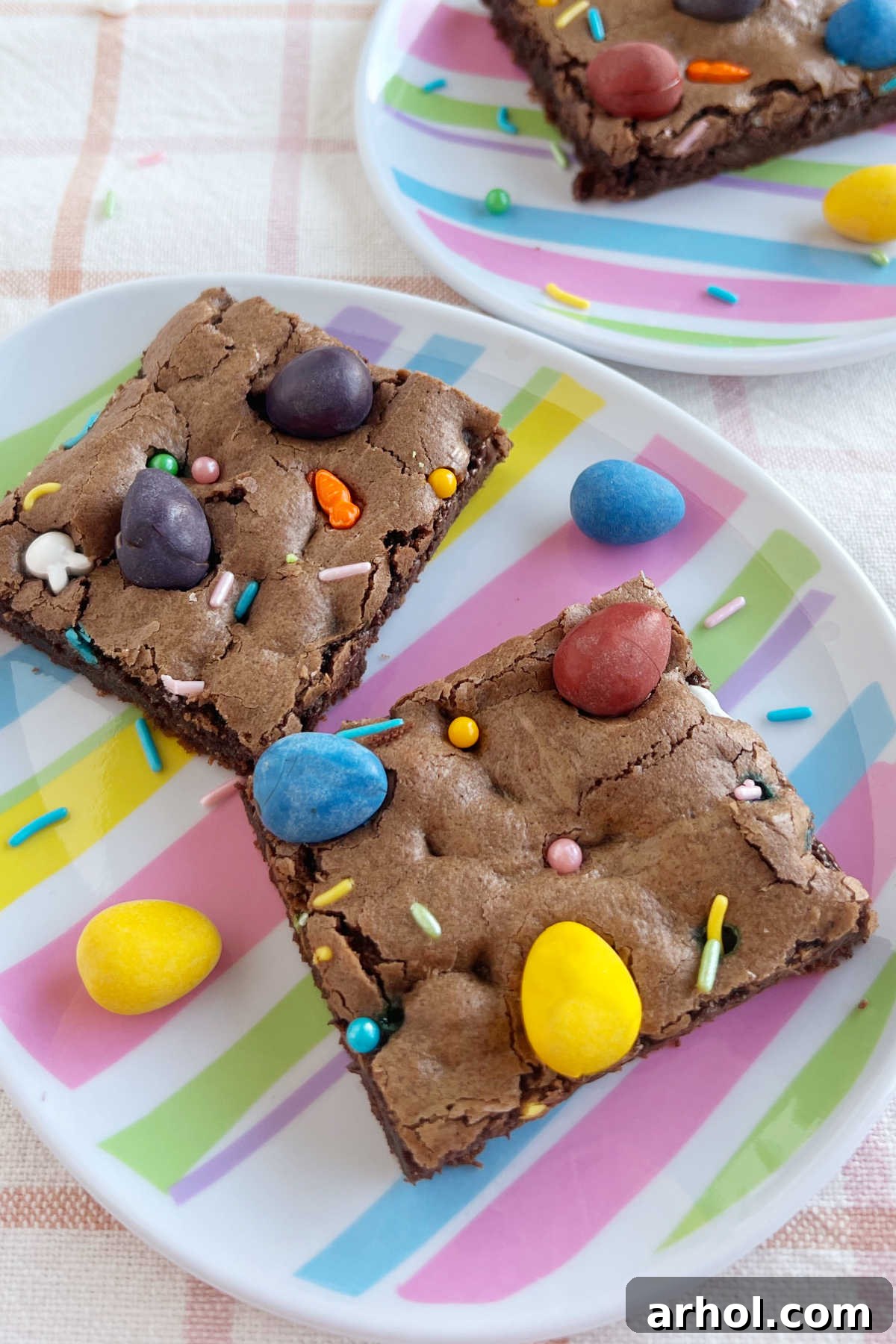 Mini Egg Magic Brownies 2 Fudgy Easter brownies topped with colorful Cadbury mini eggs on Easter egg-shaped plates, ready to serve.