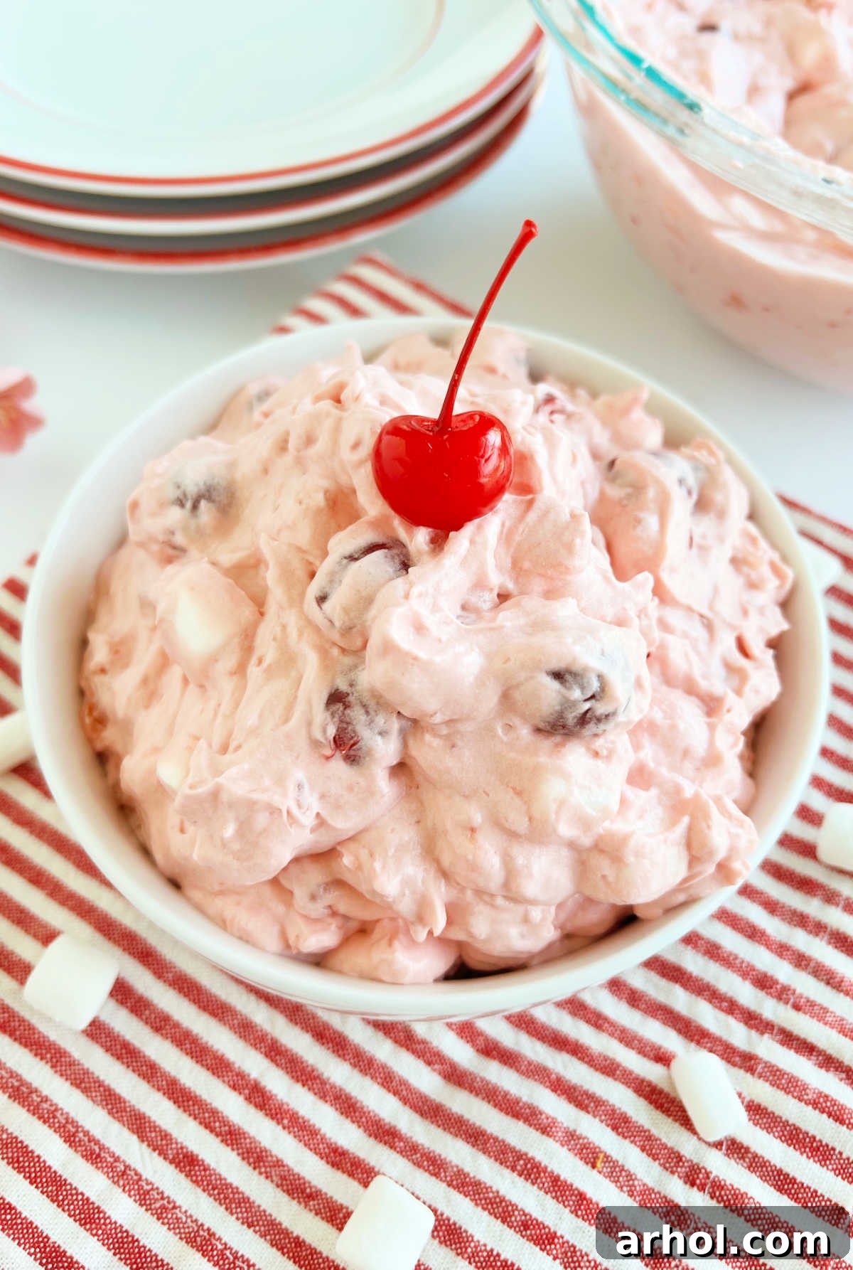 A close-up of Cherry Fluff salad in a bowl, showing its creamy texture, mini marshmallows, and visible pieces of cherry, ready for enjoyment.