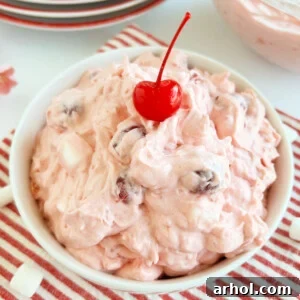 cherry fluff salad with maraschino cherry in a white bowl