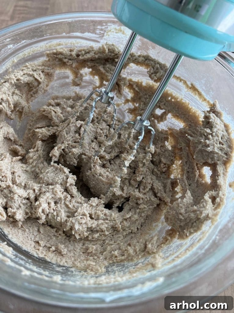 Creaming butter, brown sugar, and white sugar in a mixing bowl with an electric mixer