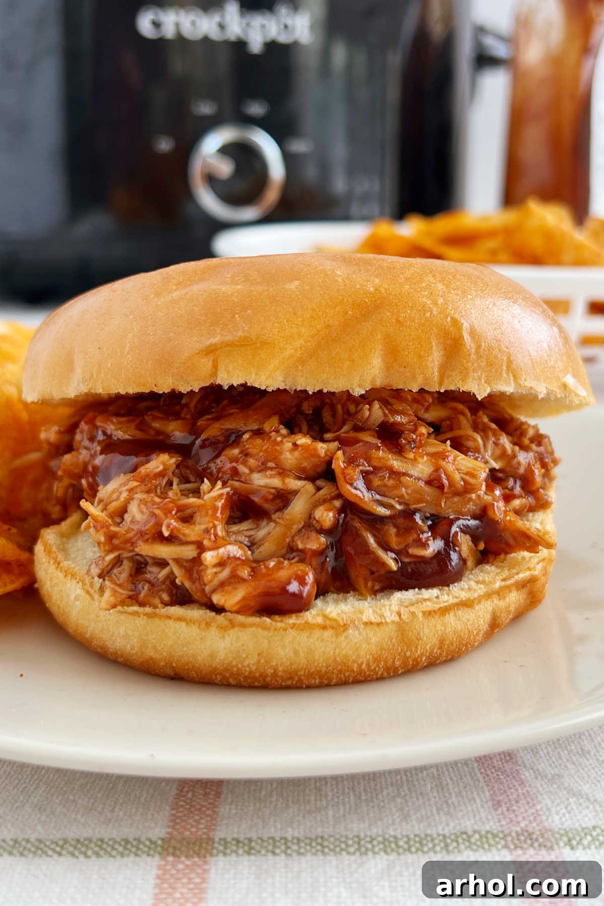 Irresistible Slow Cooker BBQ Pulled Chicken 2 crockpot BBQ chicken sandwich with pulled chicken on a plate