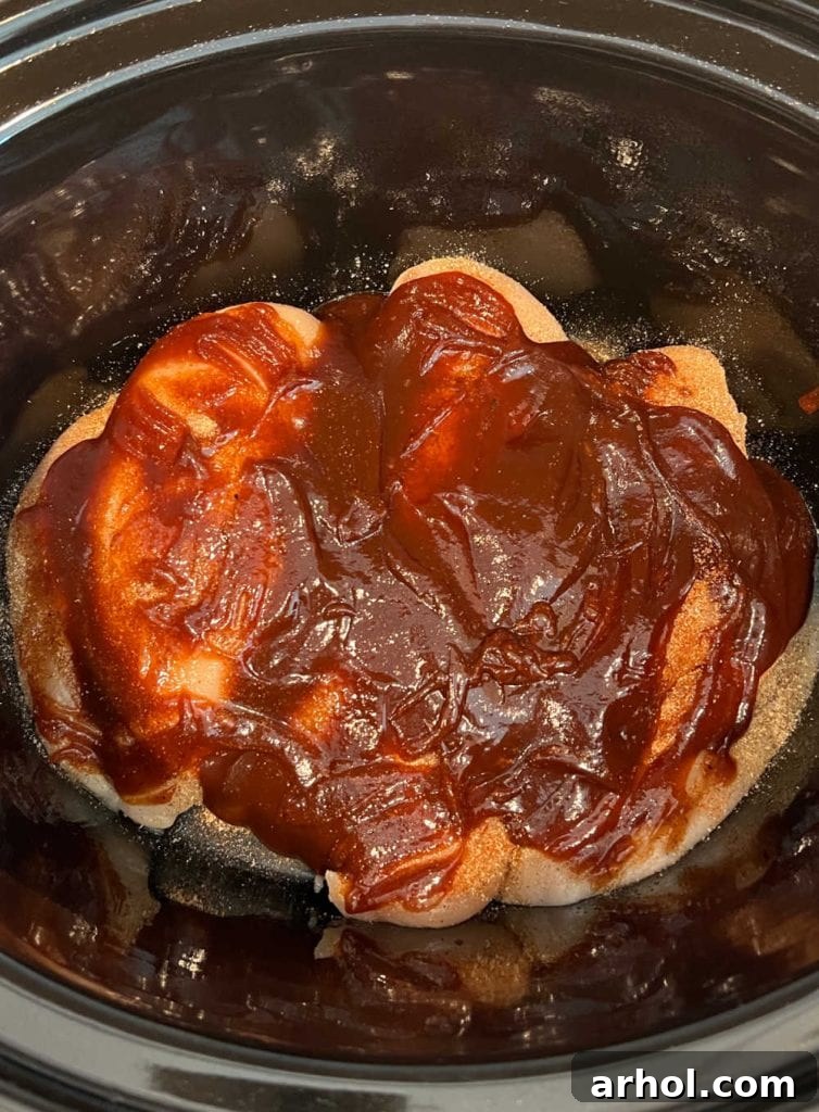 Irresistible Slow Cooker BBQ Pulled Chicken 4 chicken with seasoning and bbq sauce in slow cooker