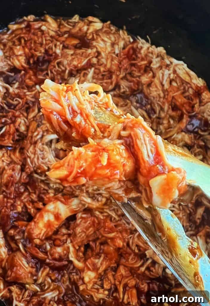 Irresistible Slow Cooker BBQ Pulled Chicken 6 slow cooker bbq pulled chicken in kitchen tongs
