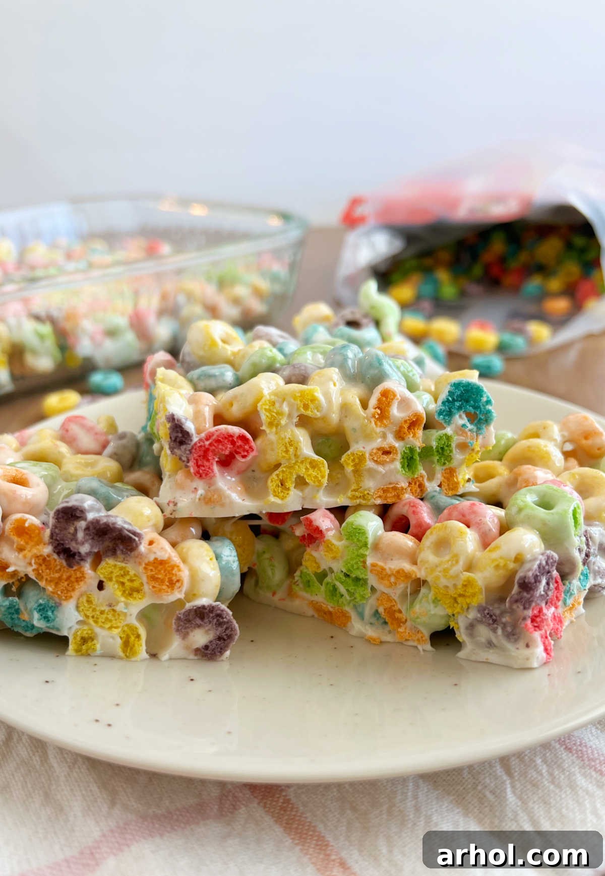 A beautiful side view of a stack of freshly made Froot Loop Bars on a white plate, highlighting their vibrant colors and perfect chewy consistency.