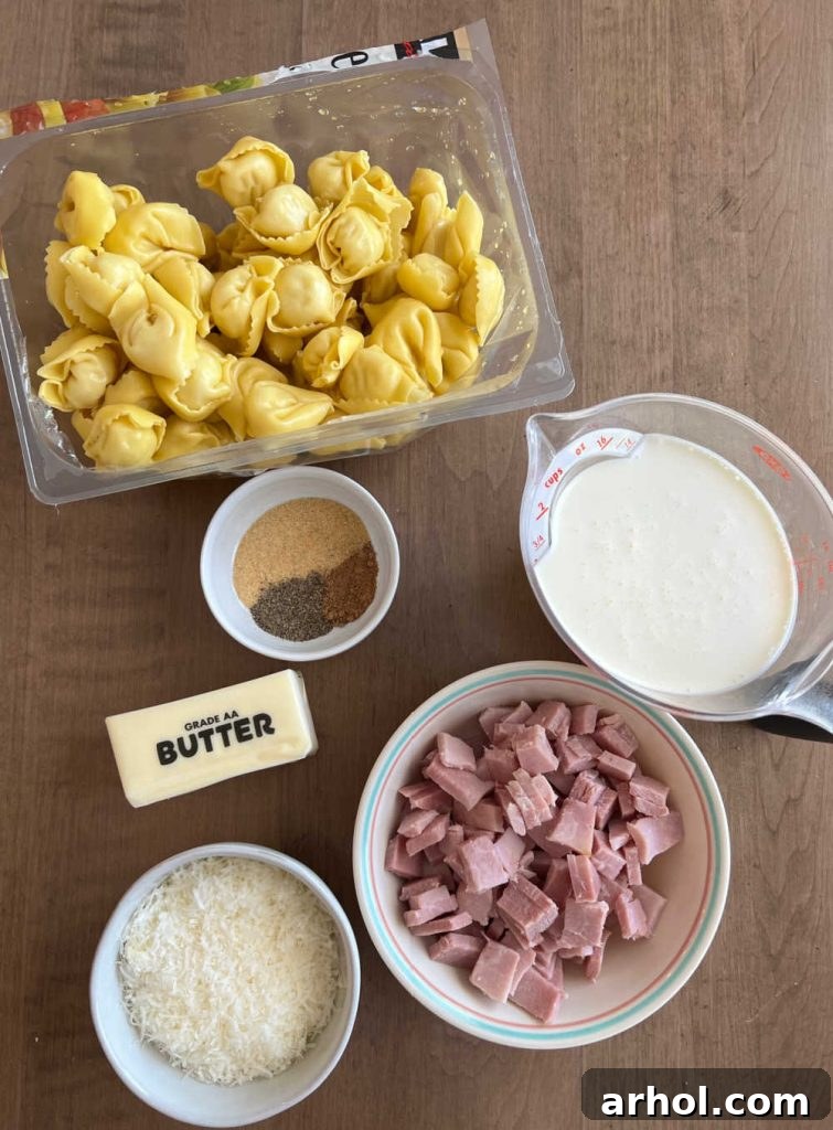 Assortment of fresh ingredients for Cheese Tortellini with Ham and Peas, including fresh tortellini, heavy cream, diced ham, butter, Parmesan cheese, and various seasonings, laid out on a wooden surface.