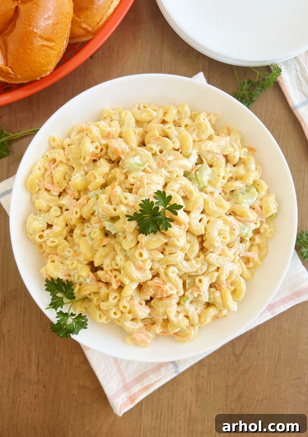 A vibrant bowl of Hawaiian macaroni salad, garnished with fresh parsley, sitting on a rustic wooden table, ready to be served.