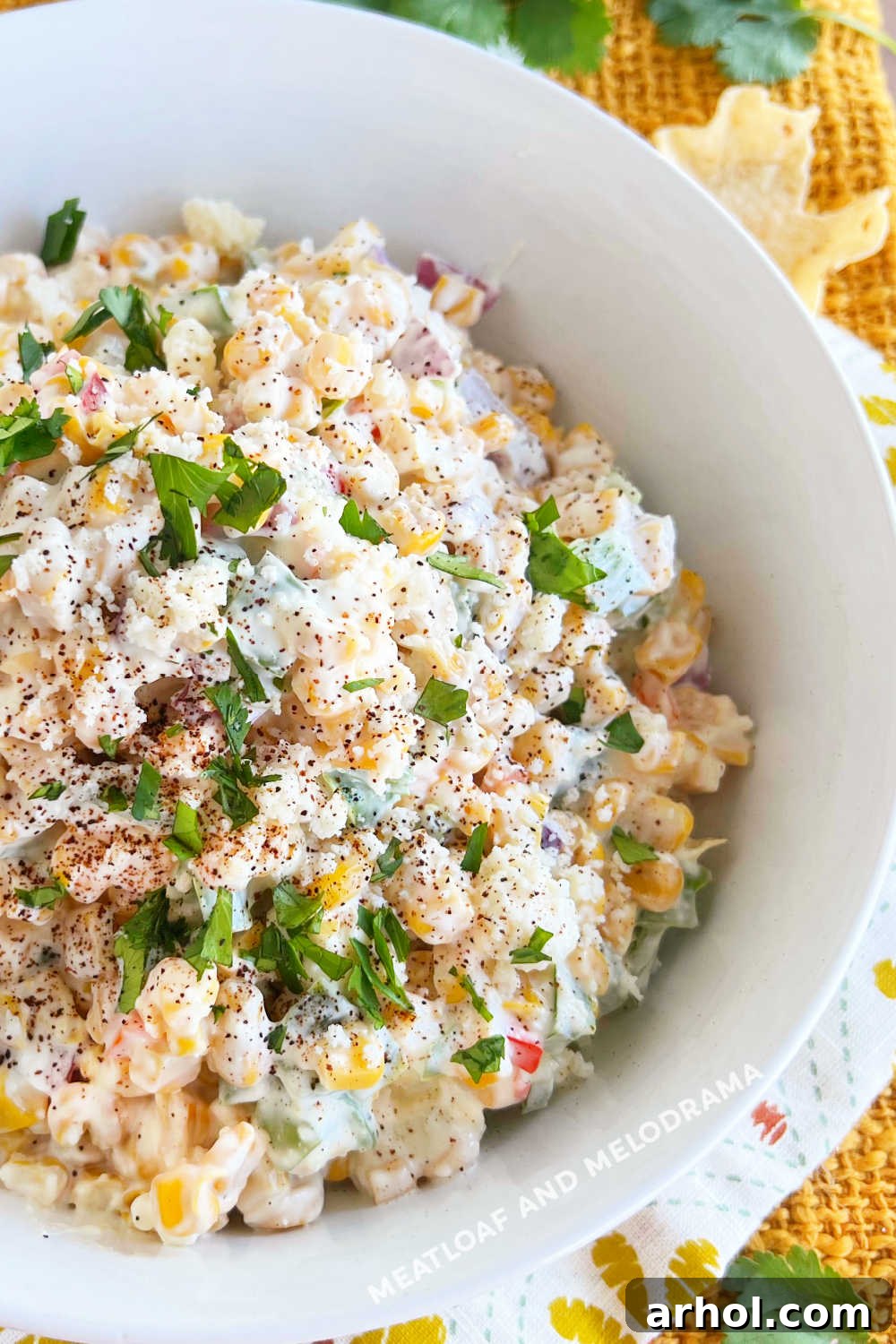 A close-up view of Mexican corn salad, garnished with vibrant green cilantro, served beautifully in a white bowl.