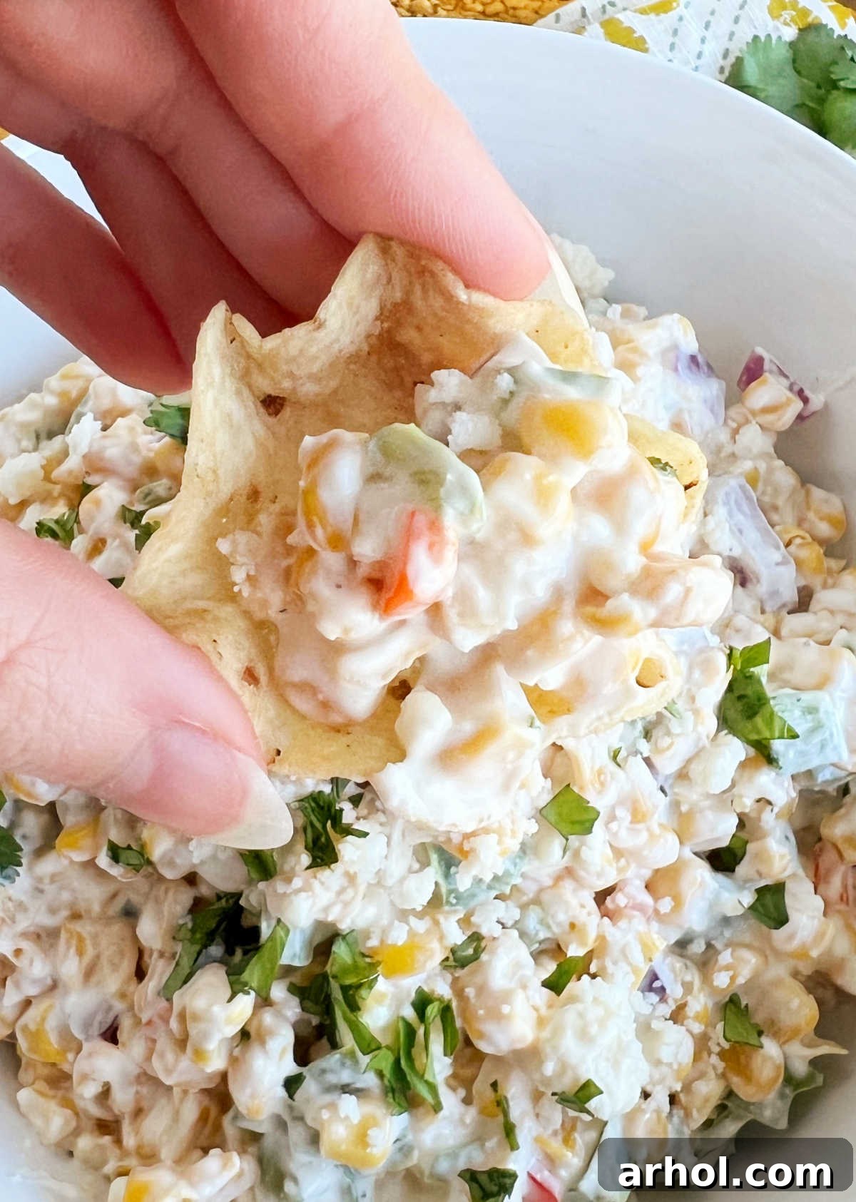 A crisp Tostitos chip generously filled with creamy Mexican street corn dip, showcasing its vibrant colors and inviting texture.