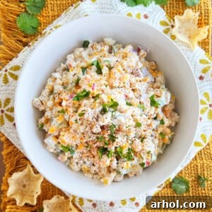 Mexican street corn salad (elote salad) topped with Cotija cheese and cilantro in a white serving bowl, a vibrant and appealing side dish.