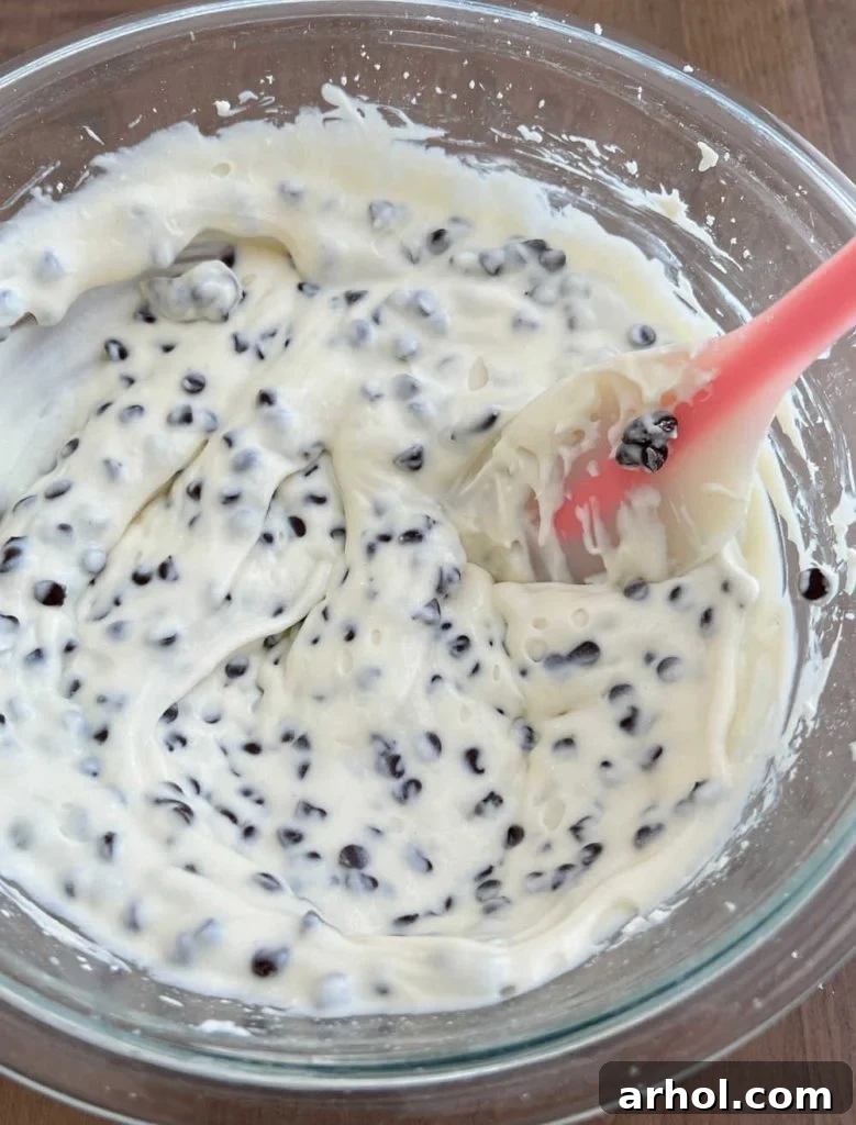 stirring cannoli dip in bowl with spatula.